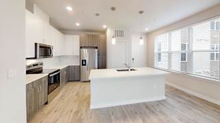 Modern kitchen island with pendant lights and large windows at Bridge at Windsor Park Apartments, Austin, Texas
