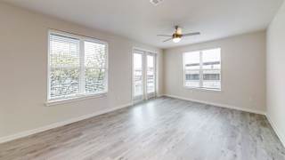 Sunlit living space with ceiling fan and patio doors at Bridge at Windsor Park Apartments, Austin