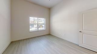 Vacant bedroom with window and laminate flooring at Cantarra Apartments, Manor, Texas