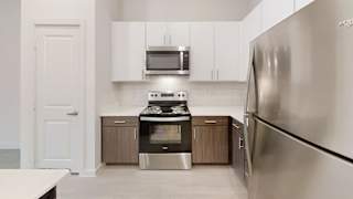 Kitchen with stainless appliances and white upper cabinets at Cantarra Apartments, Manor, TX 78653