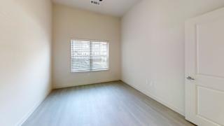 Empty bedroom with window and light wood flooring at Cantarra Apartments, Manor, Texas