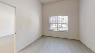 Empty bedroom with window and vinyl plank flooring at Cantarra Apartments, Texas, 78653