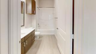 Modern bathroom with tub shower combo and wood vanity at Cantarra Apartments, Manor, TX 78653