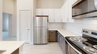 Kitchen with stainless refrigerator and wood tone lower cabinets at Cantarra Apartments, Manor