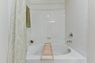 Clean white tiled bathroom with soaking tub 1 at Cantarra Apartments, Manor, Texas