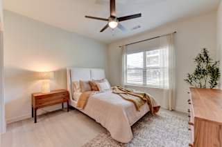 Cozy bedroom with wood furnishings and natural light 1 at Cantarra Apartments, Texas