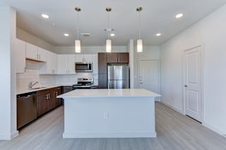 Modern kitchen with white island and wood cabinetry at Cantarra Apartments, Texas, 78653
