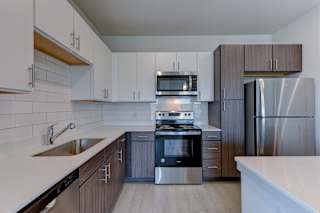 Two tone kitchen with white subway tile backsplash at Cantarra Apartments, Manor, TX
