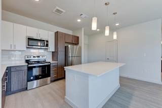 Contemporary kitchen with center island and pendant lights at Cantarra Apartments, Texas