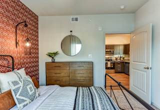 Bedroom with wood dresser and view into kitchen 1 at High Point Preserve Apartments, Austin, TX 78724