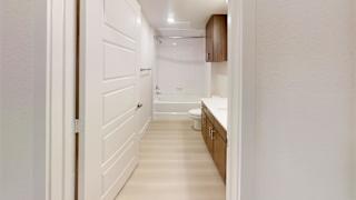 A white hallway with a toilet and sink in the distance.