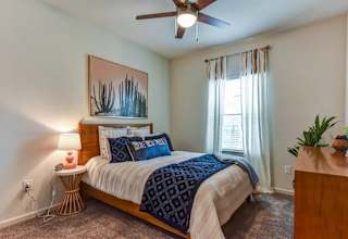Bedroom with wood bed frame and blue bedding accents 1 at High Point Preserve Apartments, Austin, Texas