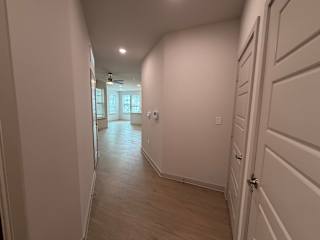 A long hallway with white walls and wood flooring.