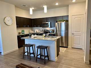 Modern kitchen with island seating and dark cabinetry at High Point Preserve Apartments, Texas, 78724