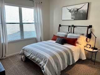 Bedroom with highland cow artwork and striped bedding at High Point Preserve Apartments, Austin