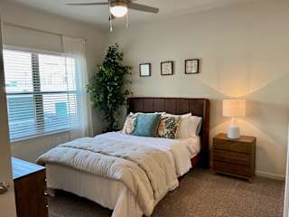 Bedroom with brown leather headboard and decorative pillows 1 at High Point Preserve Apartments, Austin, TX