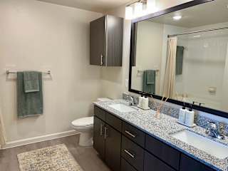 Double vanity bathroom with speckled granite and mirror 1 at High Point Preserve Apartments, Austin