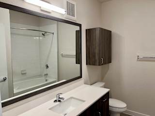 Bathroom with tub shower combo and dark wood cabinet at Bridge at Windsor Park Apartments, Austin, 78723