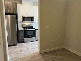 Empty room with view into modern kitchen at Bridge at Windsor Park Apartments, Austin, 78723