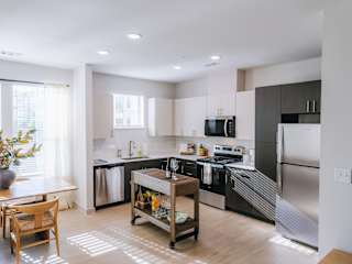 A modern kitchen with stainless steel appliances and wooden flooring.