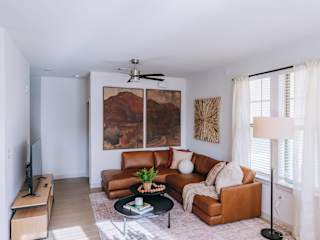 A living room with a brown leather couch and a painting on the wall.