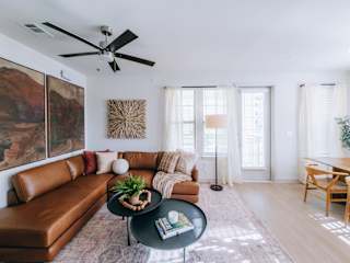 A living room with a brown leather couch, a black coffee table, and a ceiling fan.