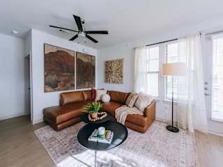 A living room with a brown leather couch, a black coffee table, and a ceiling fan.