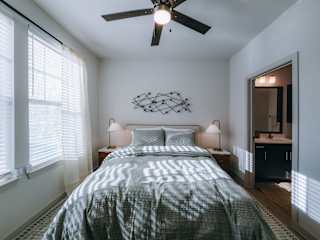 A bedroom with a bed, two lamps, and a ceiling fan.