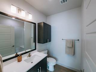 A bathroom with a white sink, toilet, and a mirror above the sink.