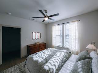 A bedroom with a large bed and a ceiling fan.