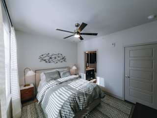 A bedroom with a bed, nightstand, and a ceiling fan.