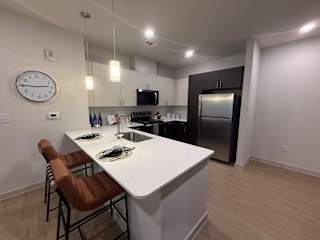 A kitchen with a white countertop and brown chairs.
