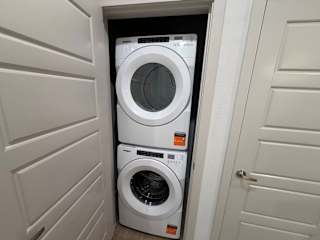 A white washing machine is in a small space between two doors.