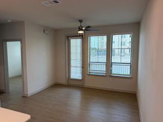A room with a ceiling fan and sliding glass doors.