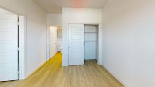 A room with white walls and wooden flooring with two white doors at Park South Apartments, Austin