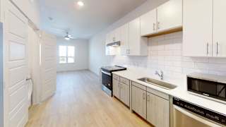 A kitchen with white cabinets and a wooden floor. at Park South Apartments, Austin, TX, 78748