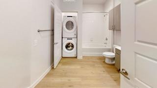 A white bathroom with a washer and dryer in the doorway. at Park South Apartments, Austin