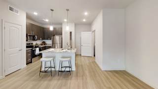 a kitchen with a large center island with two stools at Bridge at Three Hills Apartments, Texas, 78747