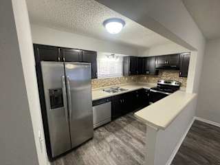 A kitchen with a stainless steel refrigerator and black cabinets