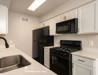 A kitchen with black appliances and white cabinets.