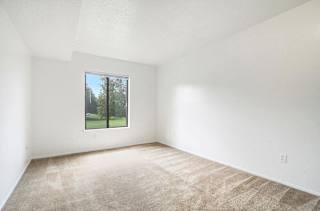 A large bedroom with a window and plush carpeting at Apple Ridge Apartments, Walker, MI, 49534