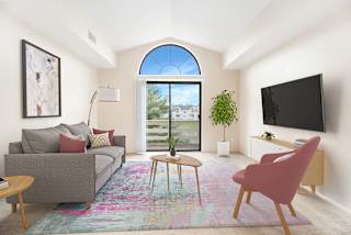 A living room with a cathedral ceiling and a grey couch at Arbor Lakes Apartments in Elkhart, IN