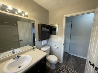 A bathroom with a sink, toilet, and mirror.