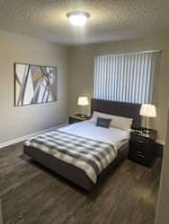 A bedroom with a bed, nightstands, and a painting on the wall.