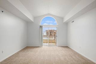 Spacious carpeted room with arched transom window and balcony access at Black Sand Apartments Homes, Lincoln, Nebraska