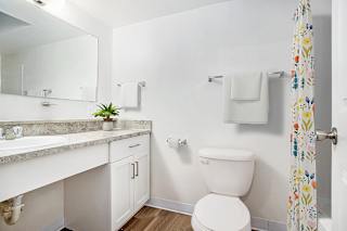 Modern bathroom with white vanity and floral shower curtain at Brentwood Park Apartments, La Vista