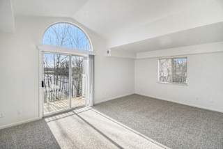 Bright living room with vaulted ceiling and patio access at Brentwood Park Apartments, La Vista, NE 68128