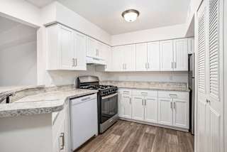 White kitchen with granite counters and gas range at Brentwood Park Apartments, La Vista, NE