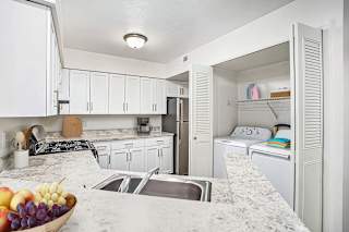 Kitchen with laundry closet and granite countertops at Brentwood Park Apartments, La Vista