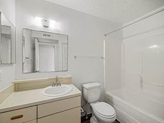 Bathroom with white tub surround and mirror at Brentwood Park Apartments, La Vista